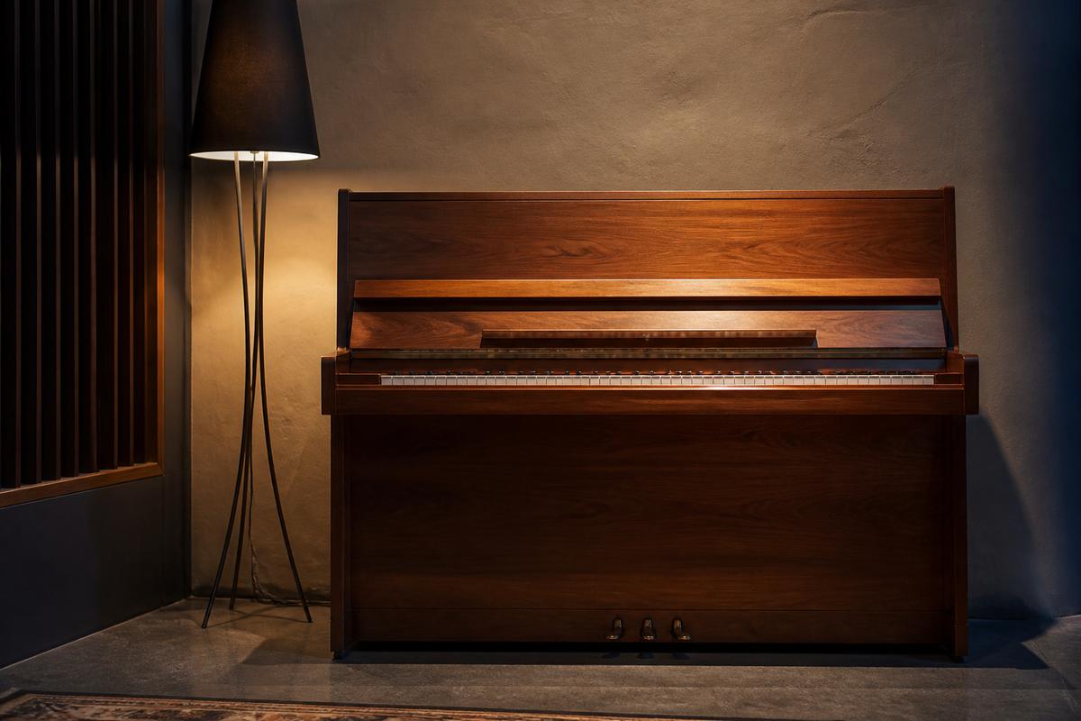 Wooden upright piano against a textured studio wall